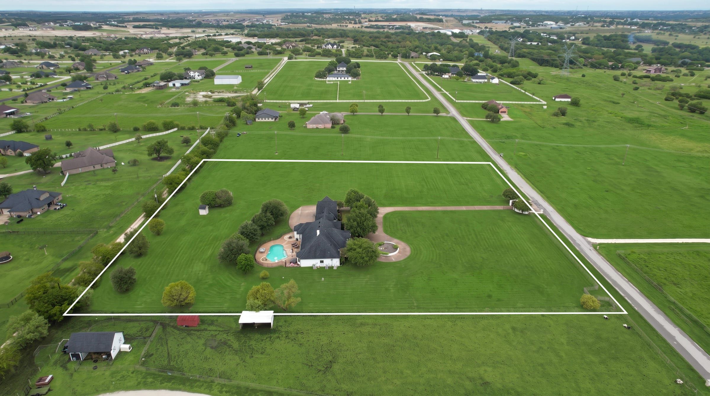 Aerial view of the full 5.01-acre property with the boundary outlined, showing the home, pool and pasture