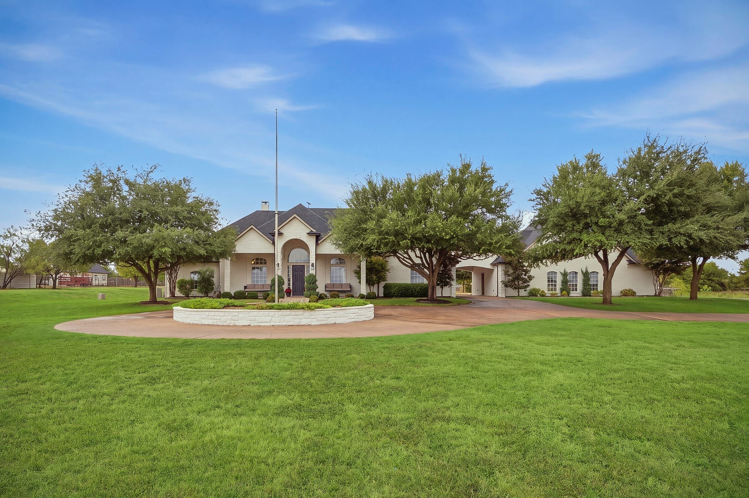 Front of the home with the circle drive and mature oak trees