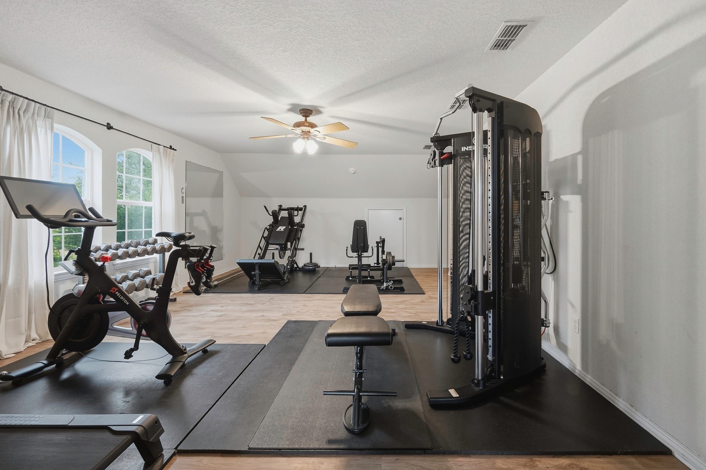 Guest suite above the garage with arched windows, currently set up as a home gym