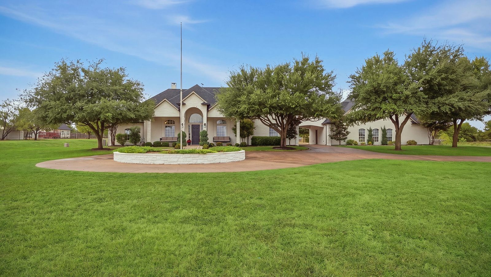 Front of the home with the arched entry, covered porch and mature oak trees