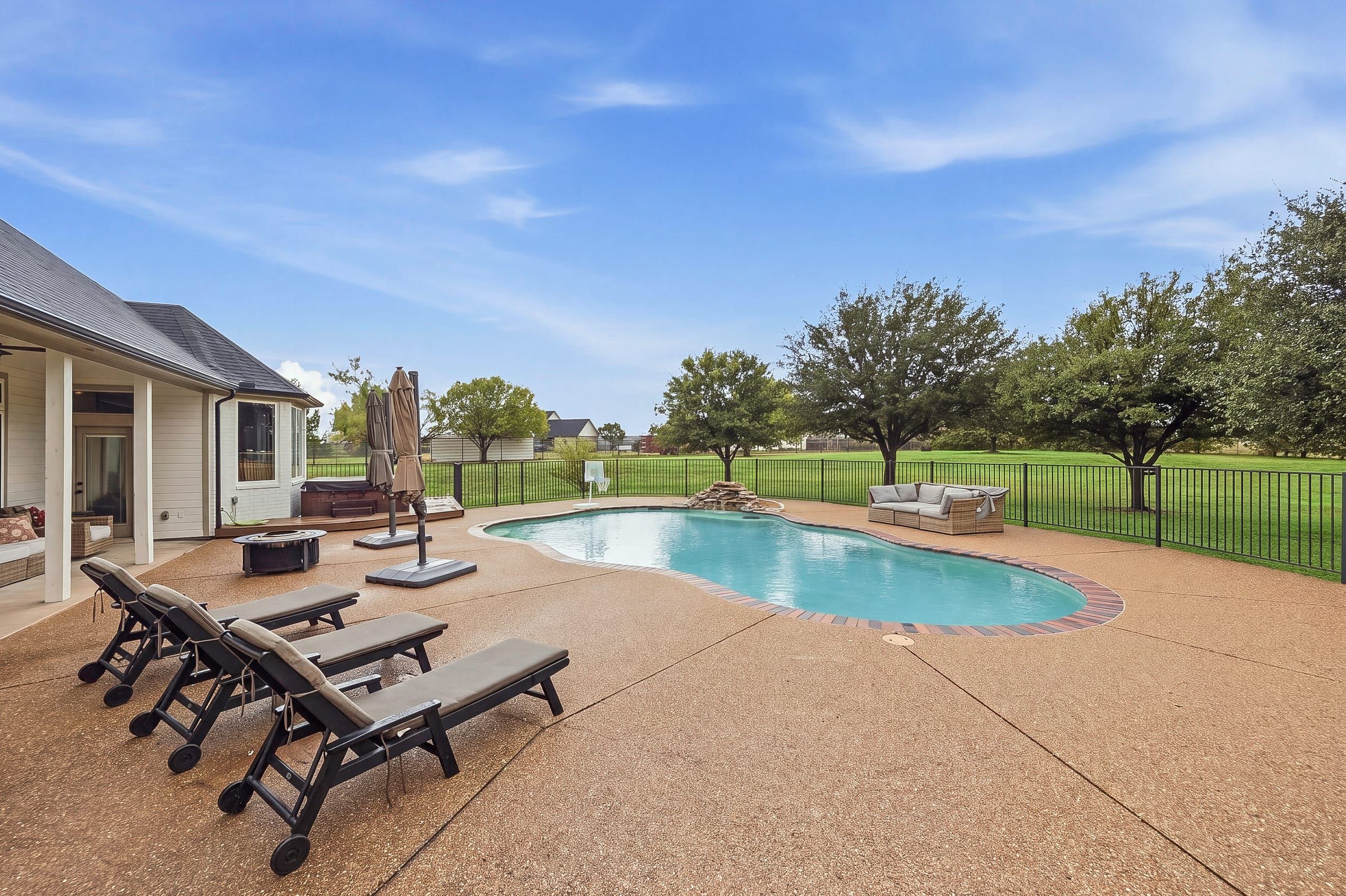 Pool deck with loungers, fire pit and rock waterfall