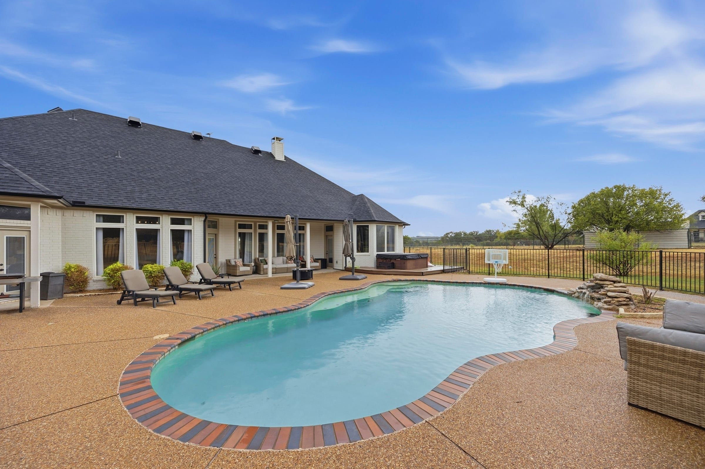 In-ground pool with the back of the home and covered patio