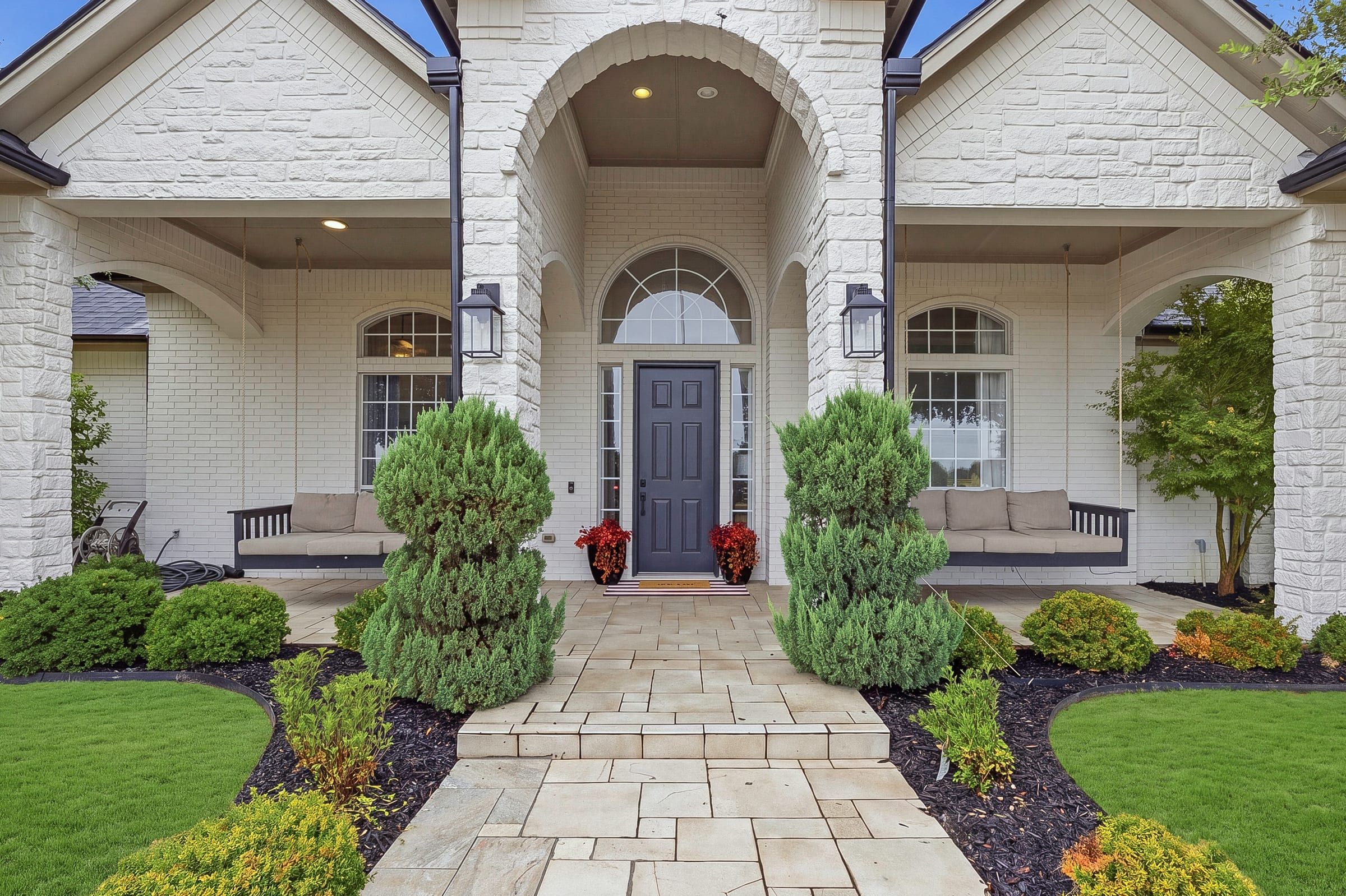 Covered front porch with two daybed swings and stone walkway
